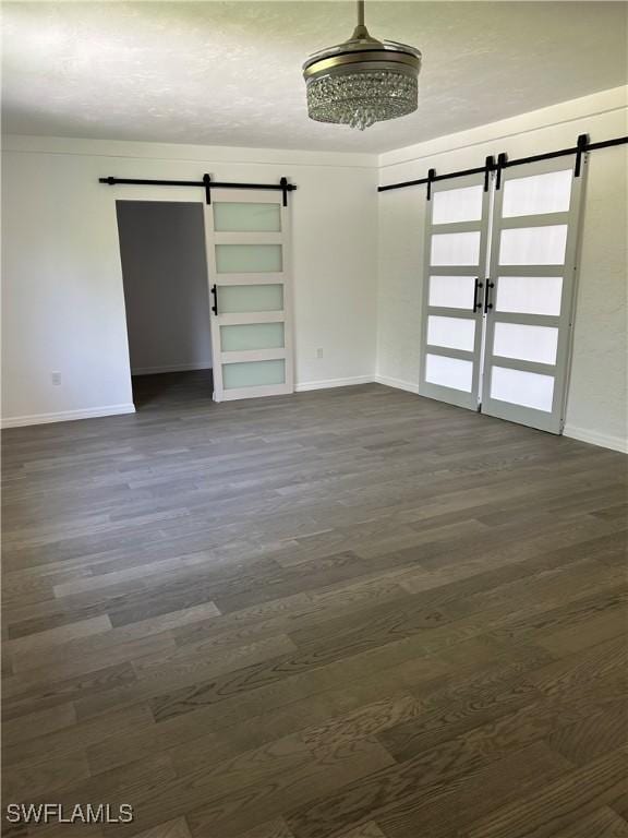 empty room featuring a barn door and dark hardwood / wood-style floors