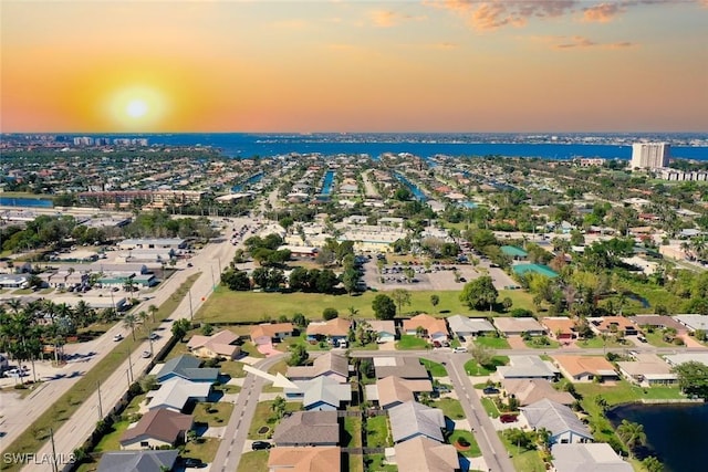 aerial view at dusk featuring a residential view and a water view