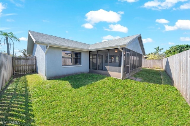 rear view of house with a sunroom, a fenced backyard, a lawn, and stucco siding