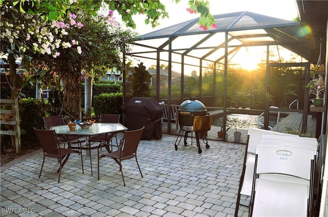 view of patio featuring glass enclosure and a grill