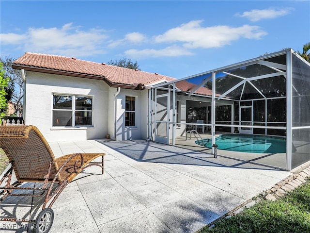 back of property featuring a patio, a lanai, a tile roof, an outdoor pool, and stucco siding