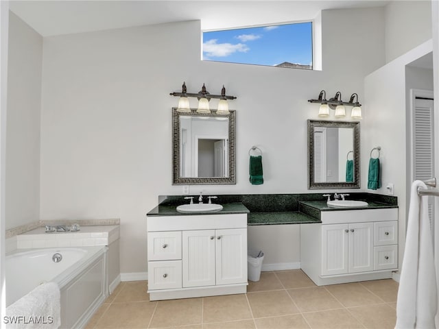 full bath featuring baseboards, a sink, tile patterned flooring, a washtub, and two vanities