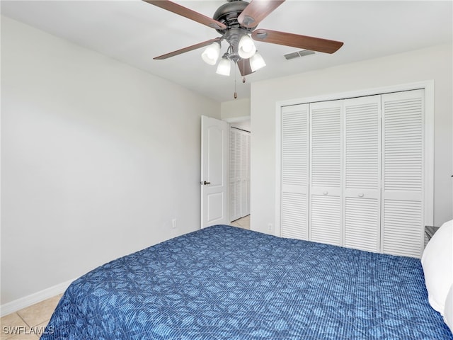 unfurnished bedroom with baseboards, visible vents, ceiling fan, tile patterned floors, and a closet