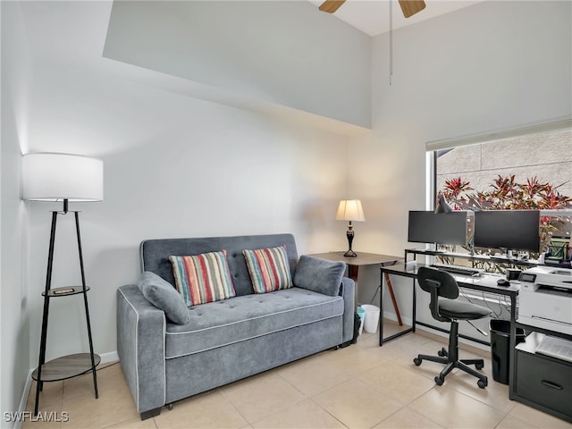 home office featuring a high ceiling, baseboards, a ceiling fan, and light tile patterned flooring