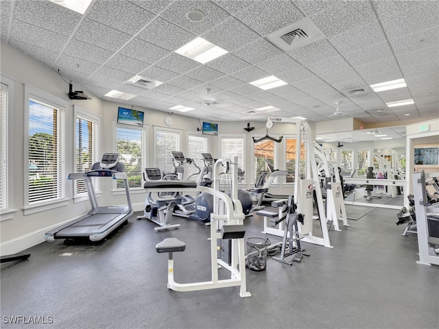 exercise room with visible vents, a drop ceiling, and baseboards