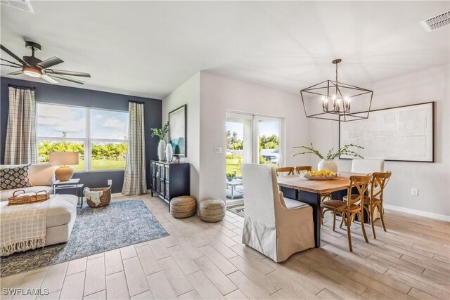 dining area with light wood-style floors, visible vents, baseboards, and ceiling fan with notable chandelier
