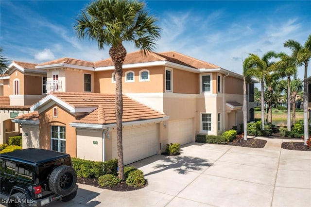 view of front of house featuring concrete driveway, a tiled roof, a garage, and stucco siding