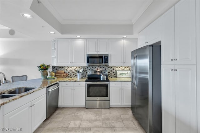 kitchen featuring stainless steel appliances, a sink, white cabinets, light stone countertops, and crown molding