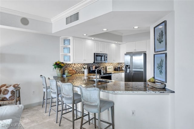 kitchen featuring stainless steel appliances, a peninsula, visible vents, white cabinetry, and dark stone countertops