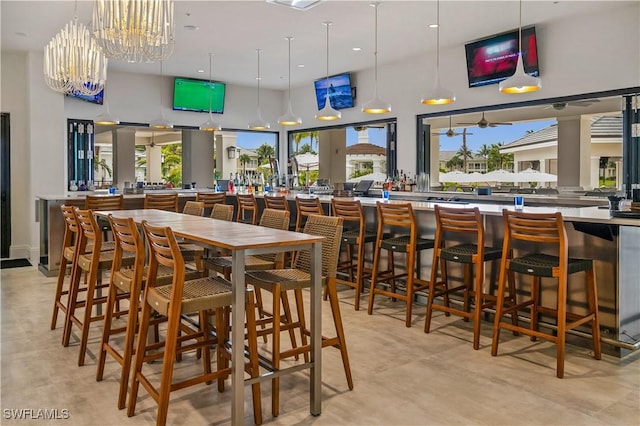 dining room featuring a chandelier, a community bar, and a high ceiling