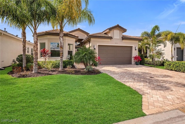 mediterranean / spanish-style home featuring a garage, a front lawn, decorative driveway, and stucco siding