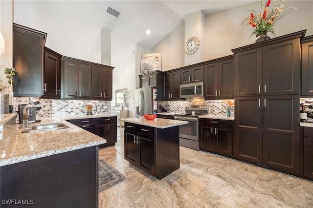 kitchen featuring a center island, stainless steel appliances, visible vents, a sink, and light stone countertops