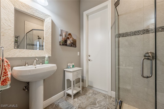 full bath with a stall shower, a sink, and baseboards