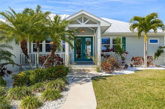 property entrance with metal roof, a lawn, and french doors