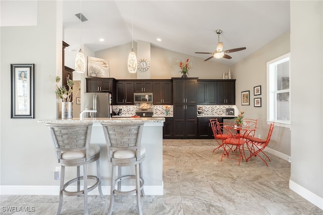 kitchen featuring visible vents, decorative backsplash, lofted ceiling, stainless steel appliances, and pendant lighting