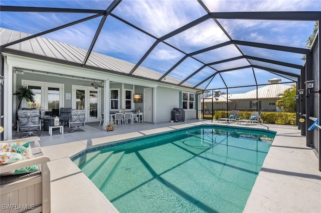 pool featuring glass enclosure, french doors, a patio, and a ceiling fan