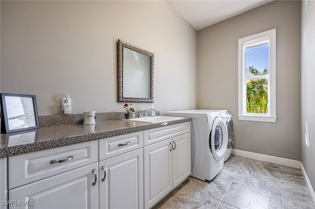 laundry area with cabinet space, baseboards, separate washer and dryer, and a sink