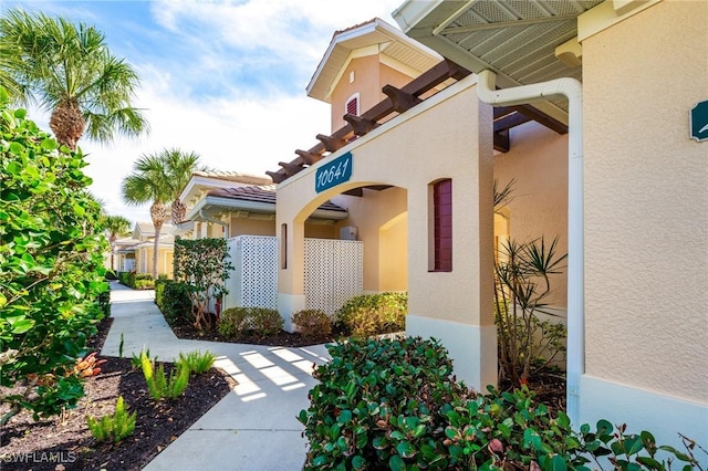 property entrance featuring a tiled roof and stucco siding