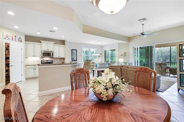 dining room with light tile patterned floors, ceiling fan with notable chandelier, and visible vents