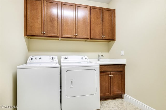 clothes washing area featuring light tile patterned floors, washing machine and clothes dryer, cabinet space, and baseboards