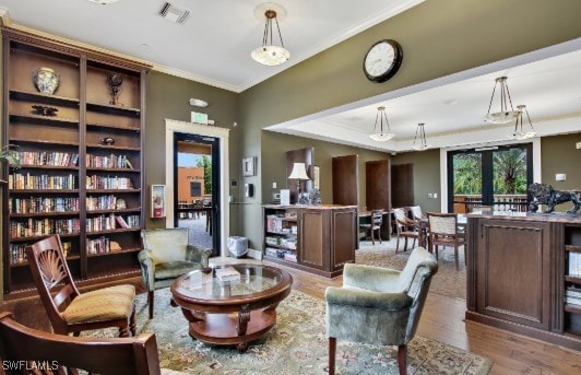 living area featuring visible vents, wood finished floors, and ornamental molding