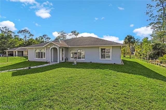 view of front of home featuring fence, a front lawn, and stucco siding