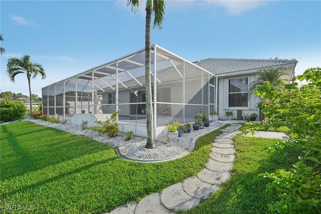 rear view of property featuring glass enclosure and a lawn