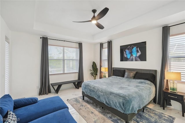 bedroom with ceiling fan and a raised ceiling