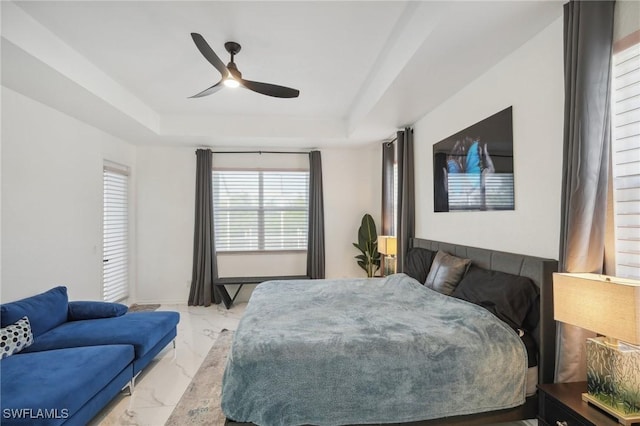 bedroom with ceiling fan and a tray ceiling