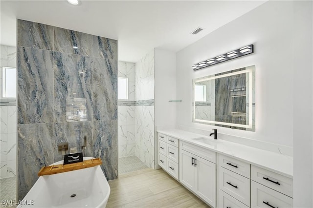 bathroom with a freestanding tub, visible vents, walk in shower, and vanity