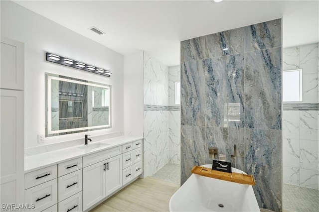 bathroom featuring visible vents, walk in shower, a freestanding bath, and vanity