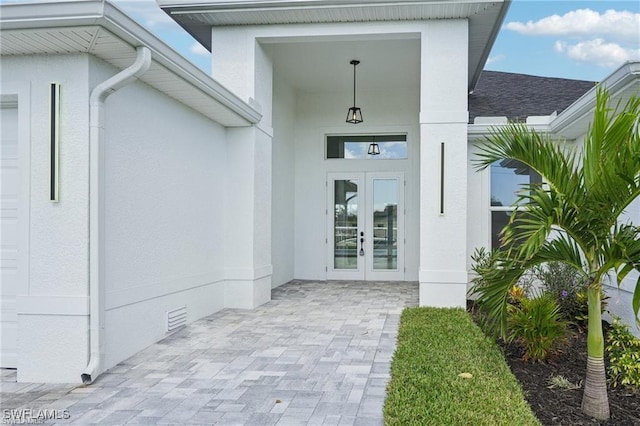 property entrance featuring a garage, roof with shingles, crawl space, french doors, and stucco siding