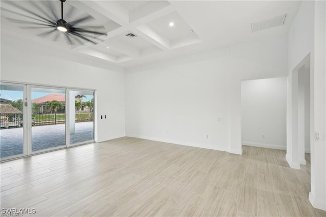 unfurnished room featuring visible vents, light wood-style flooring, coffered ceiling, and a towering ceiling