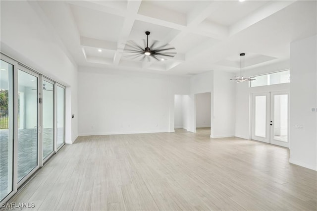 unfurnished room featuring light wood-style flooring, french doors, ceiling fan, and a towering ceiling