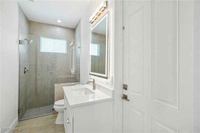 bathroom featuring a stall shower, vanity, toilet, and wood finished floors