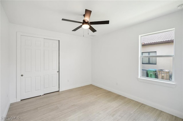 unfurnished bedroom with light wood-style floors, a closet, multiple windows, and baseboards