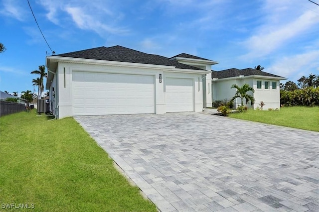 ranch-style house featuring decorative driveway, stucco siding, a front yard, fence, and a garage