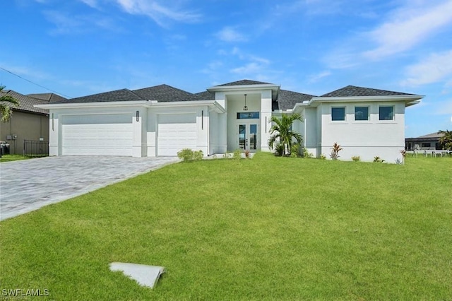 prairie-style house featuring a front lawn, decorative driveway, an attached garage, and stucco siding