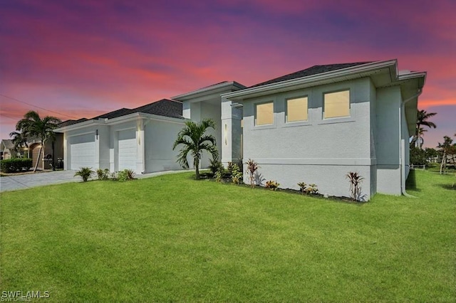 view of front facade featuring a garage, a front yard, driveway, and stucco siding