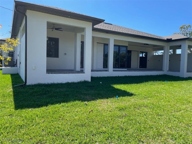 back of house with a lawn, a sunroom, ceiling fan, and stucco siding