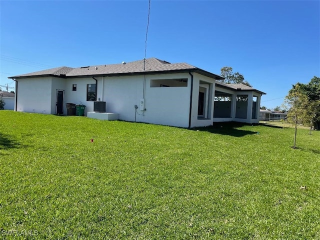 back of property with a yard and stucco siding