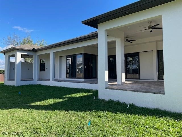 back of house with a yard, a patio area, ceiling fan, and stucco siding