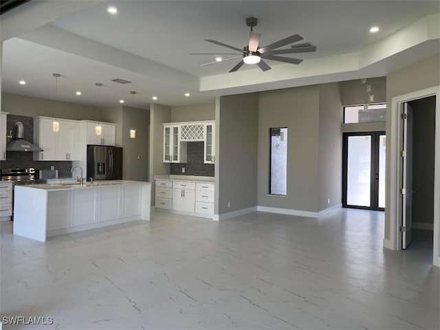 kitchen featuring baseboards, open floor plan, appliances with stainless steel finishes, wall chimney range hood, and marble finish floor