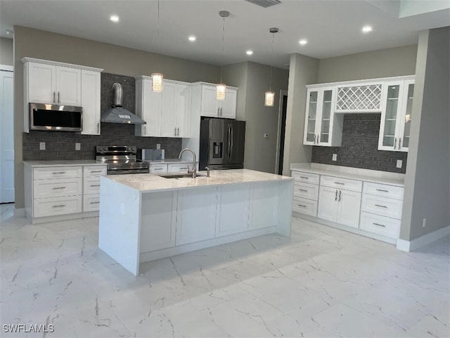 kitchen featuring wall chimney range hood, white cabinets, marble finish floor, stainless steel appliances, and a sink