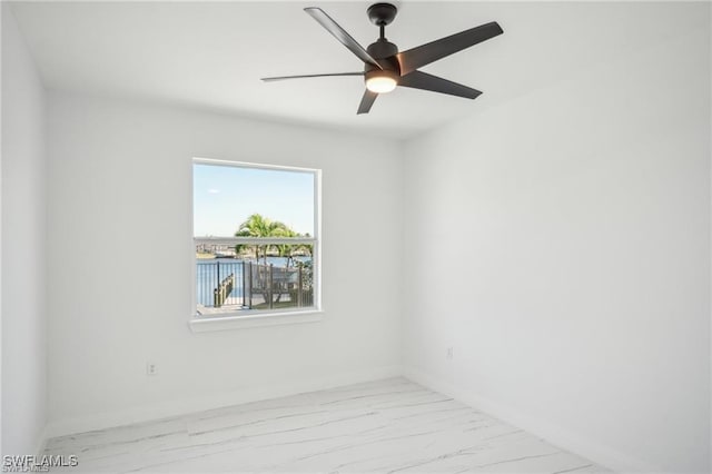 spare room featuring marble finish floor, ceiling fan, and baseboards