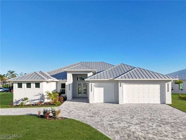 modern farmhouse featuring metal roof, decorative driveway, a standing seam roof, and an attached garage