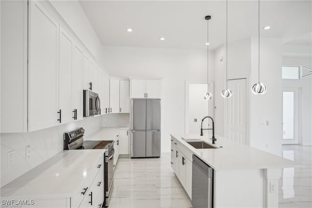 kitchen featuring a towering ceiling, stainless steel appliances, light countertops, white cabinetry, and a sink