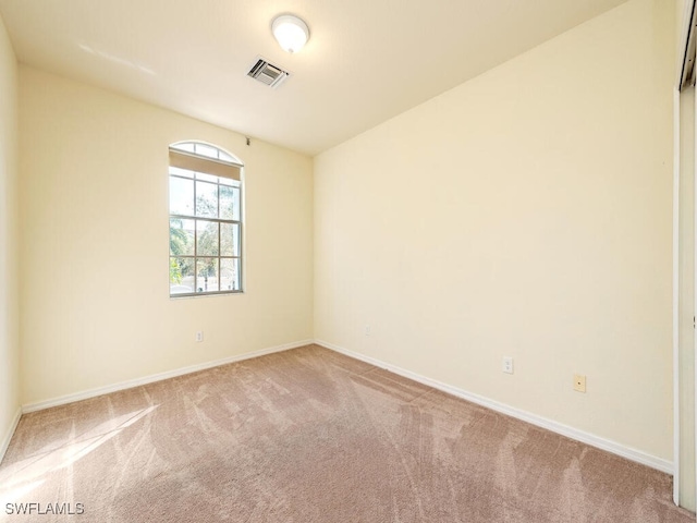 unfurnished room with baseboards, visible vents, and light colored carpet