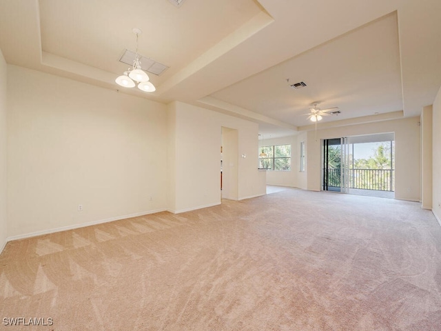 spare room featuring visible vents, a raised ceiling, baseboards, light colored carpet, and ceiling fan with notable chandelier