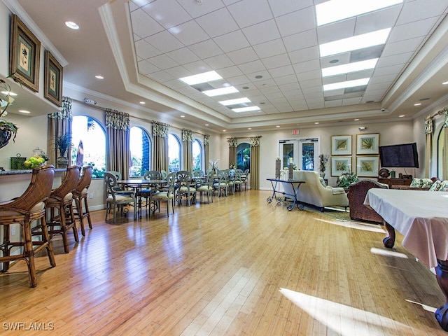 dining room with light wood-style flooring, a tray ceiling, and crown molding